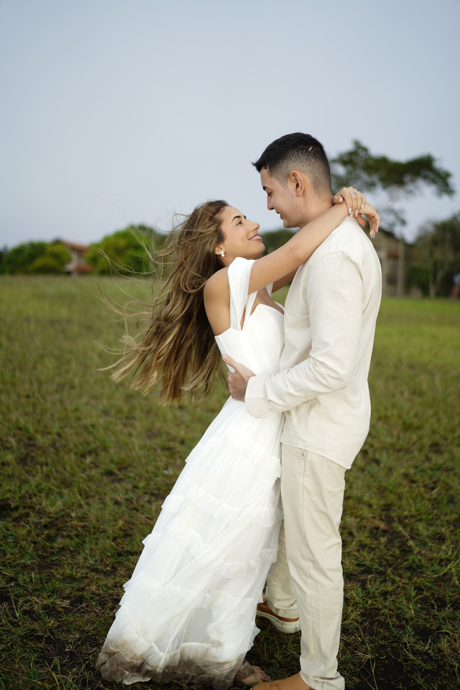 Danielle e Felipe abraçados num campo aberto, o vestido dela esvoaçando